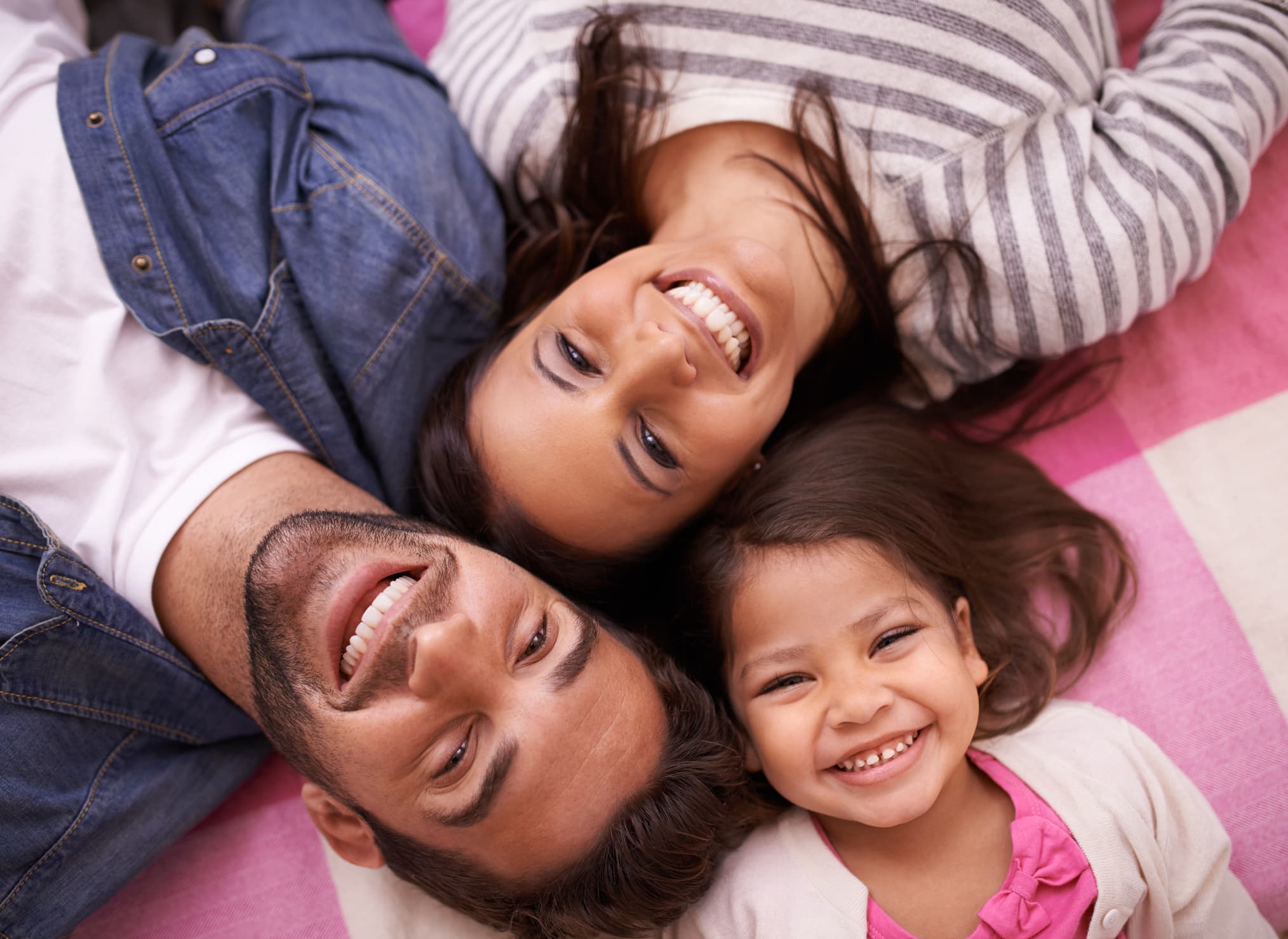 High angle portrait of a happy young family lying on their backs at home