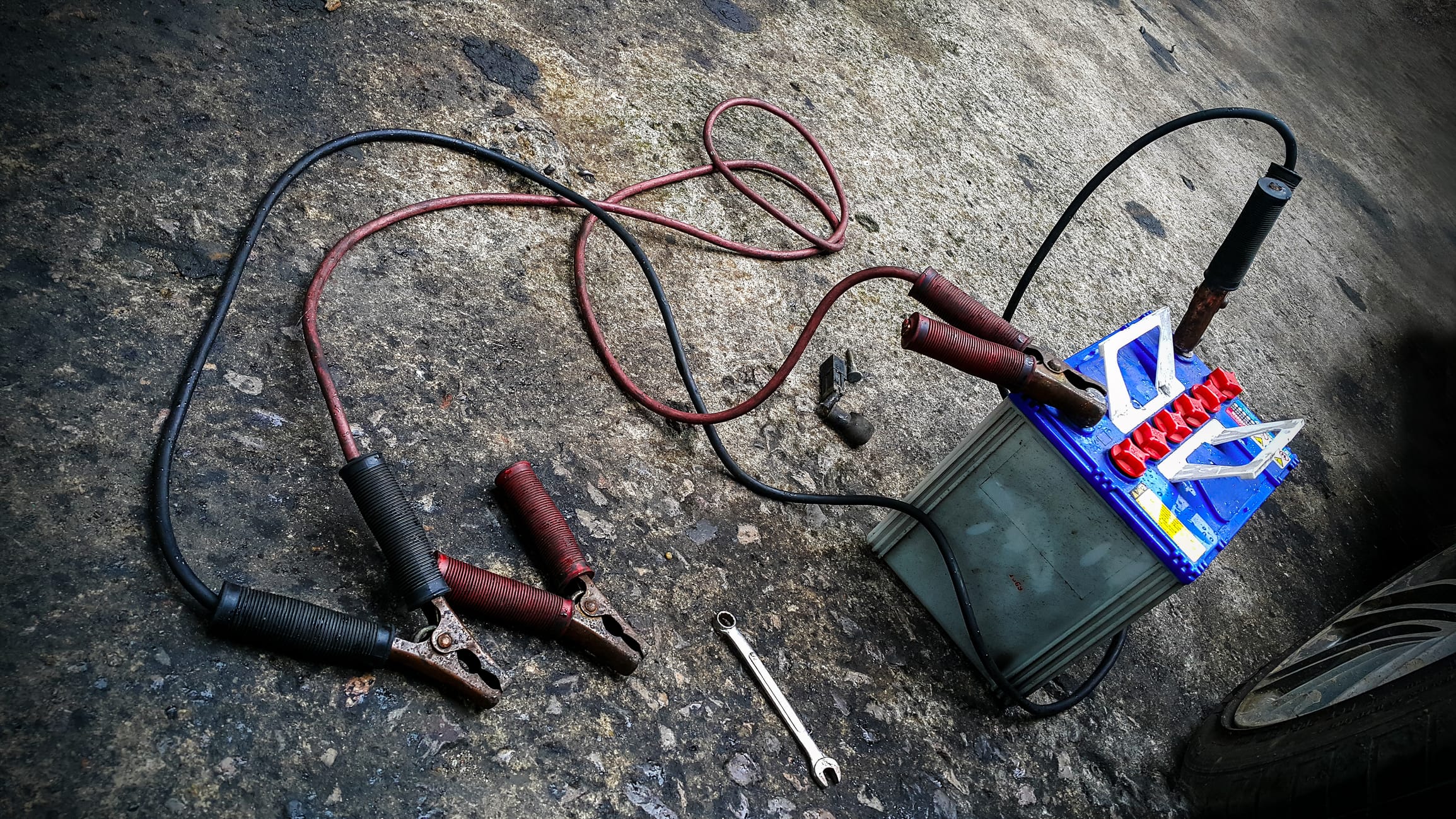A Car battery with red and black battery Jumper Cables with copper clamps