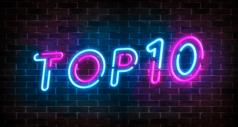Top 10 neon blue and pink light text on empty red brick wall banner. Bright sign of top ten list winners at night. Design template of modern signboard or advertising.